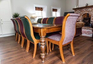 A dining room with a wooden table surrounded by six chairs with upholstered backs. - Nelly Daly's Barn - Sleeps 6 - Brand New - Parking (Newry)