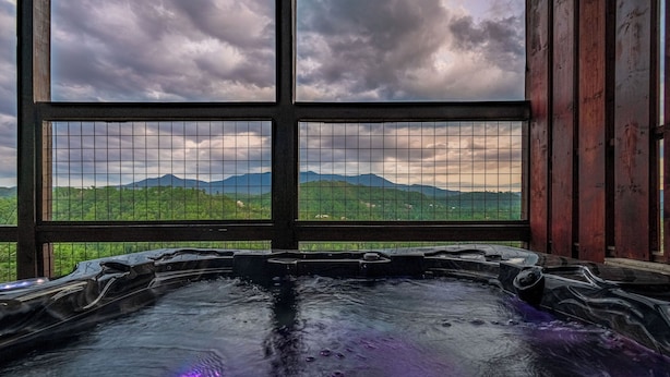 A hot tub with a view of mountains through a window. - Private Indoor Pool, Hot Tub, Free Attractions, Pool Table, Fire Pit (Gatlinburg)