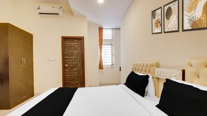 A hotel room with a large bed, a wardrobe, a door, and a window with curtains. - Classic HBR Layout Formerly Leela Park (Bengaluru)