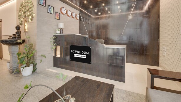 A reception area with a 'Townhouse' sign, a reception desk, a statue, and a potted plant. - Classic HBR Layout Formerly Leela Park (Bengaluru)
