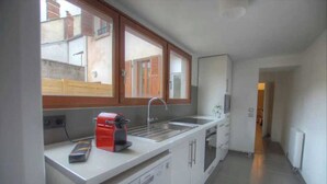 Cozinha compacta com forno embutido, pia e janela sobre o balcão.