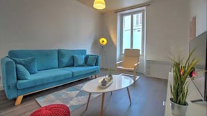 Sala de estar moderna com um sofá azul, uma mesa de centro branca e uma luminária pendente amarela.