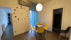 Uma sala de jantar com uma mesa redonda, cadeiras amarelas e um relógio de parede.