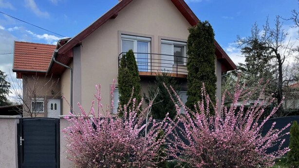 A two-story house with a red roof, a balcony, and a black gate. - Lavender Apartment (Siófok)