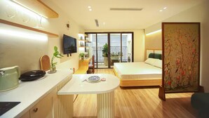 Una habitación de hotel moderna con kitchenette, zona de comedor, cama y balcón con vistas.