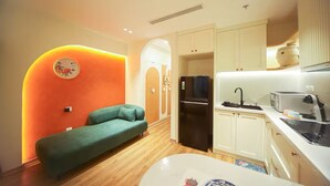 Un espacio habitable pequeño con kitchenette, un sofá y una pequeña mesa de comedor.