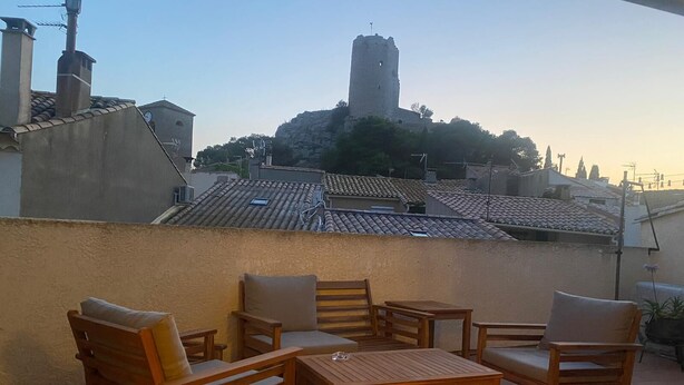 En terrasse med træmøbler og udsigt til et historisk tårn.