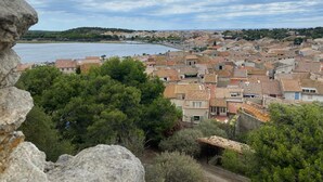 En kystby med terracotta-tag på bygningerne, et vandområde og en stengrundvold i forgrunden.