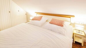 Une chambre à coucher avec un grand lit, deux tables de chevet et une tête de lit en bois.