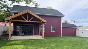 Un bâtiment rouge avec un garage fermé et une cour gazonnée.