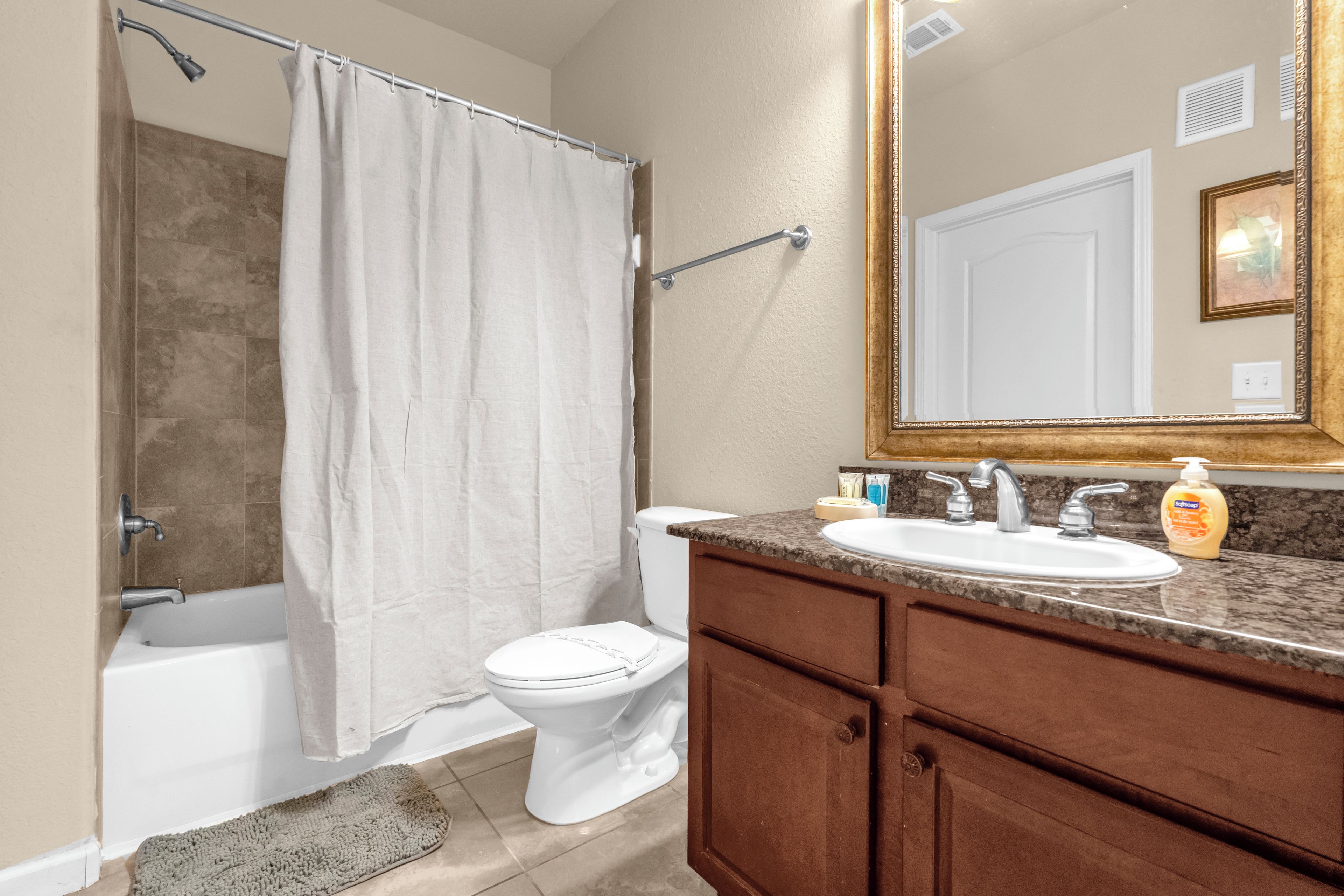 A bathroom with a bathtub, toilet, and vanity with a sink and mirror.