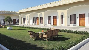 Un pati d'hotel amb zona de menjador, seients a l'aire lliure i un camí que condueix a l'edifici.