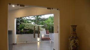 A modern interior with a glass door leading to a garden. A decorative vase is visible on the right. - SHULEM BOUTIQUE HOTEL (Dimapur)