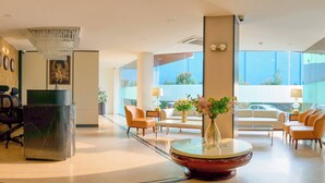 A spacious lobby with a grand chandelier, a reception desk, comfortable seating, and large windows offering a view of the outdoors. - SHULEM BOUTIQUE HOTEL (Dimapur)