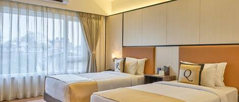 A hotel room with two beds, a large window with sheer curtains, and a city view.