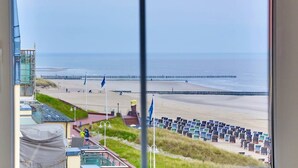 A beach view with a pier, beach umbrellas, and a lifeguard tower. - Beach Villa Marina 26 Sea View (Wangerooge)