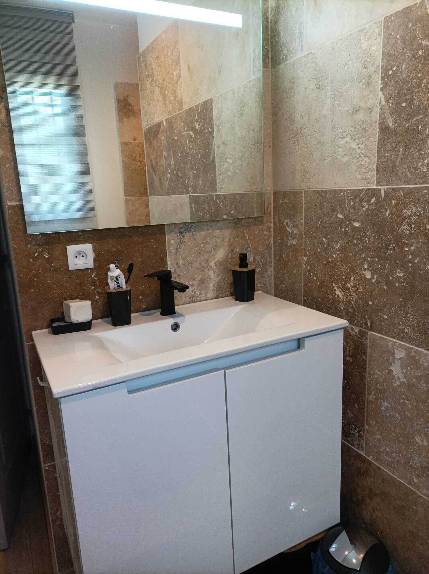Une salle de bain avec un meuble-lavabo blanc, un miroir et un évier.