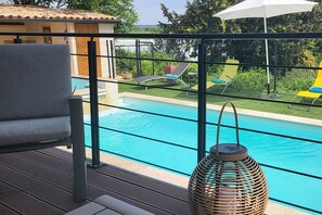 Ein Poolbereich mit Blick auf ein Schwimmbecken, eine Liege und eine Korblampe.