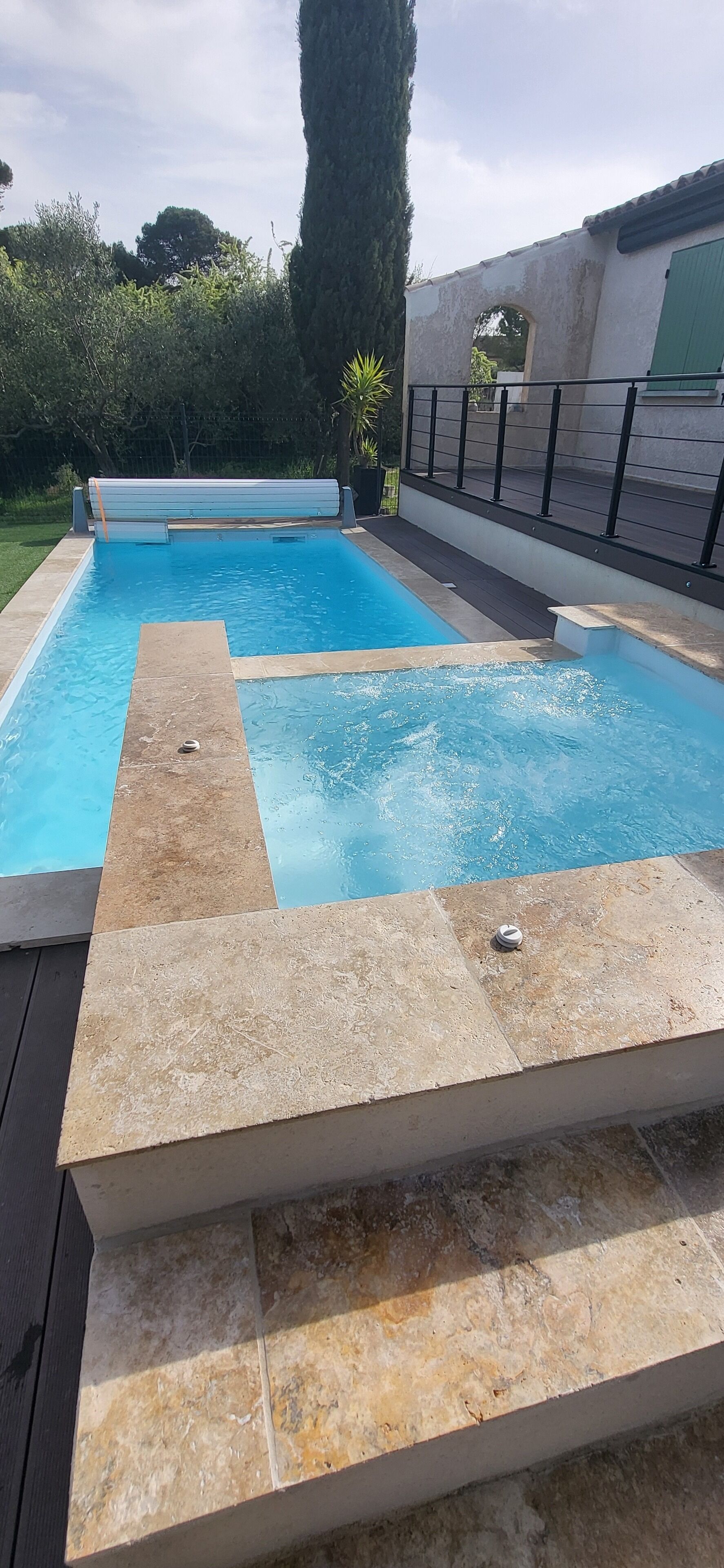Ein rechteckiger Swimmingpool mit Fliesen umrandet und einem Metallgeländer.