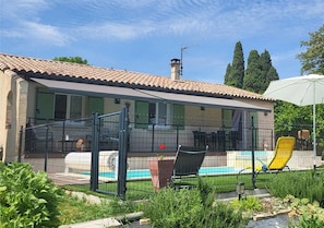 Une maison avec une piscine, un patio clos et une chaise.