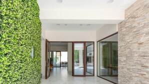 A modern interior with a green vertical garden wall, a marble floor, and a glass door leading to an outdoor area. - Zavos Aqua Park Club Apt (Limassol)