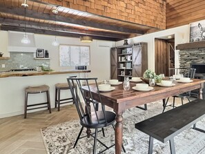 A dining area with a wooden table set for four, a black metal chair, and a bench. - Holiday Haus- Fireplace, Game Room, NearTrails! (Killington)