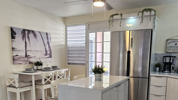 Una cocina moderna con armarios blancos, una isla central y un refrigerador de acero inoxidable.