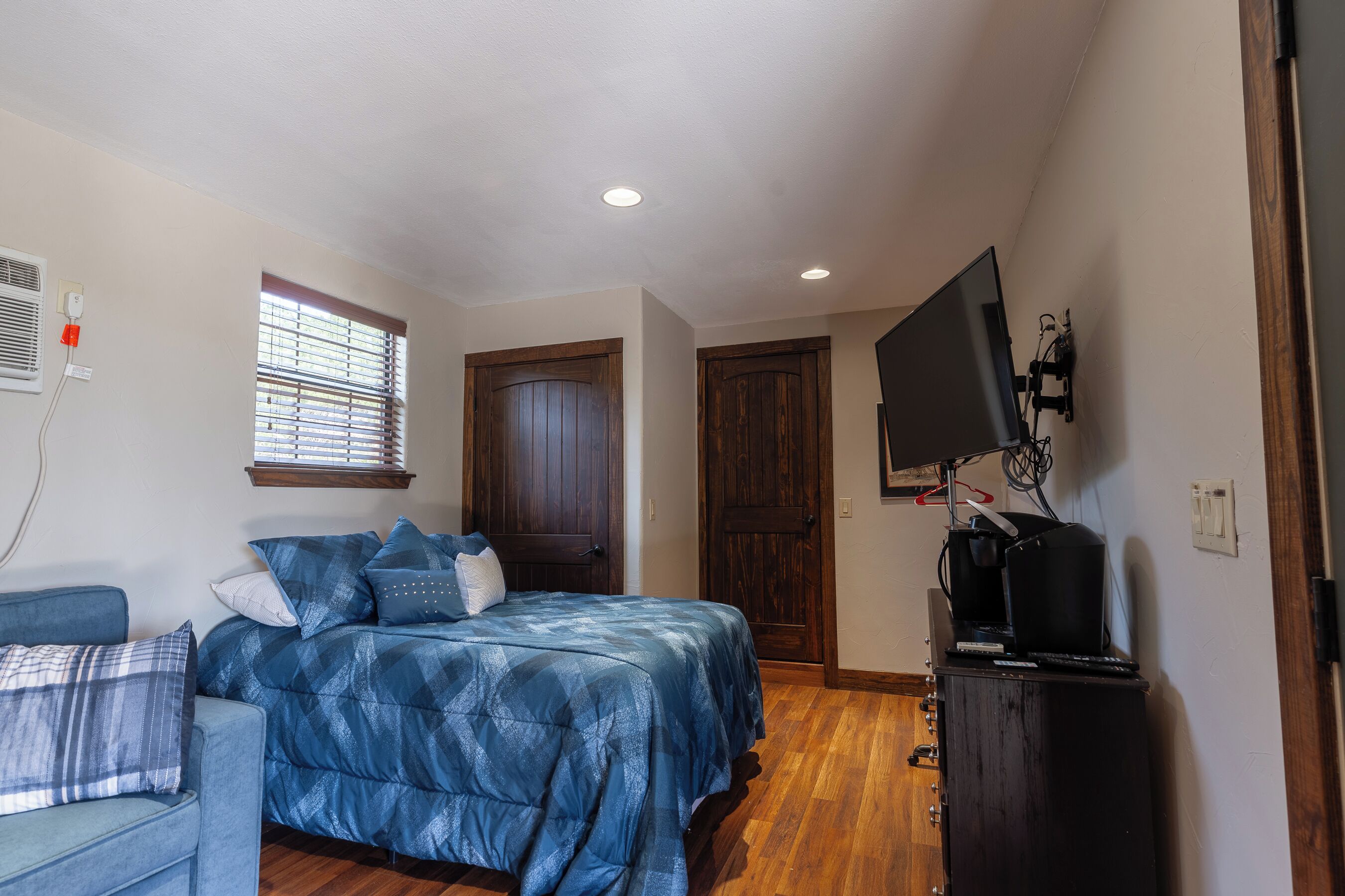 A bedroom with a bed, a TV, a desk, and a wardrobe.