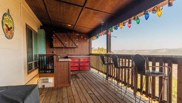 Eine Holzterrasse mit Küchenbereich, inklusive Spüle und roten Schubladen, mit Blick auf die Berge.