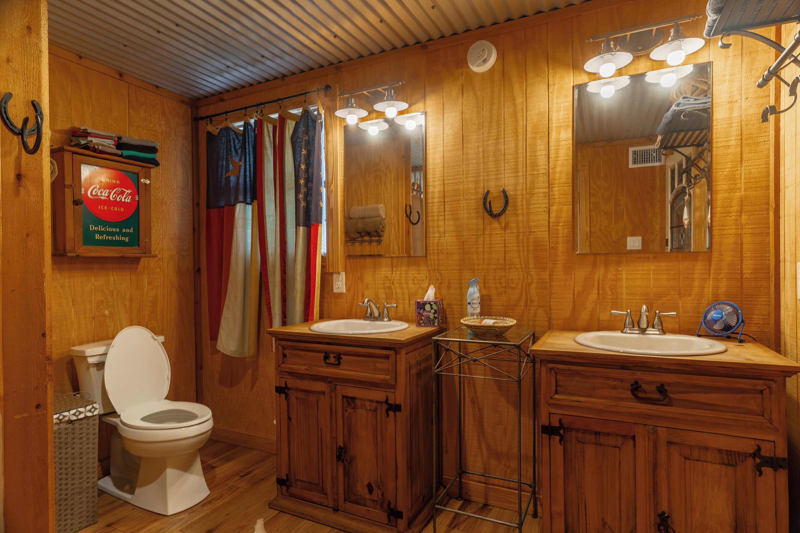 Une salle de bain en bois avec deux lavabos, des toilettes et un miroir.