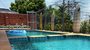 A clear blue pool with a floating ring, surrounded by a brick wall and metal fencing.