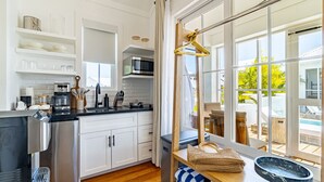 Een moderne keuken met witte kasten, roestvrijstalen apparatuur en een groot raam met uitzicht op een zwembad.