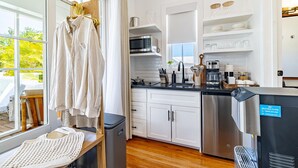 A modern kitchen with white cabinets, stainless steel appliances, and a view of the outdoors.
