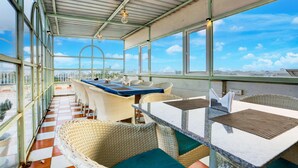 A covered outdoor seating area with wicker furniture and a view of the city. - Mordern Rooftop Restro and Pool at Udaipur (Udaipur)