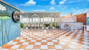 A checkered floor, a wall with a mural, and a building with a sign reading "Belle Vue". - Mordern Rooftop Restro and Pool at Udaipur (Udaipur)