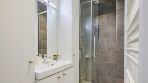 A modern bathroom with a white vanity, a glass shower enclosure, and a tiled shower floor. - Charming Apartment - 2br/4p- Javel (Paris)