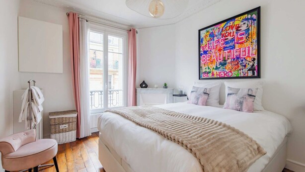 A bedroom with a large bed, a chair, a window with curtains, and a colorful artwork on the wall. - Charming Apartment - 2br/4p- Javel (Paris)