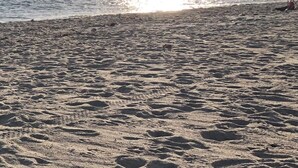 A beach with footprints and a chair in the sand.