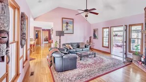 A spacious living room with a dark leather sofa, a patterned rug, and a ceiling fan. - Rustic Elegance: Farmhouse Retreat In Covington (Covington)
