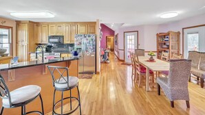 A spacious kitchen with wooden cabinets, a stainless steel refrigerator, and a dining area with a wooden table and wicker chairs. - Rustic Elegance: Farmhouse Retreat In Covington (Covington)
