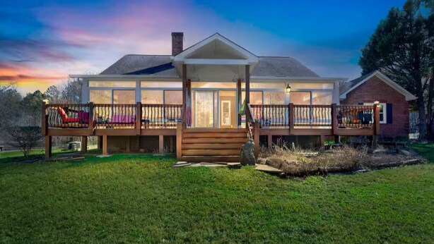 A two-story house with a covered porch, a front door, and a small brick extension. - Rustic Elegance: Farmhouse Retreat In Covington (Covington)