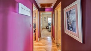 A hallway with wooden flooring, pink walls, and framed artwork. - Rustic Elegance: Farmhouse Retreat In Covington (Covington)