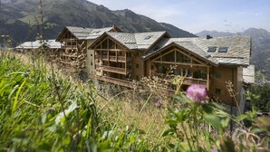 A chalet-style building with multiple balconies, set against a mountainous backdrop. - Apartment in Sainte-foy With Ski-in/ski-out (Sainte-Foy-Tarentaise)