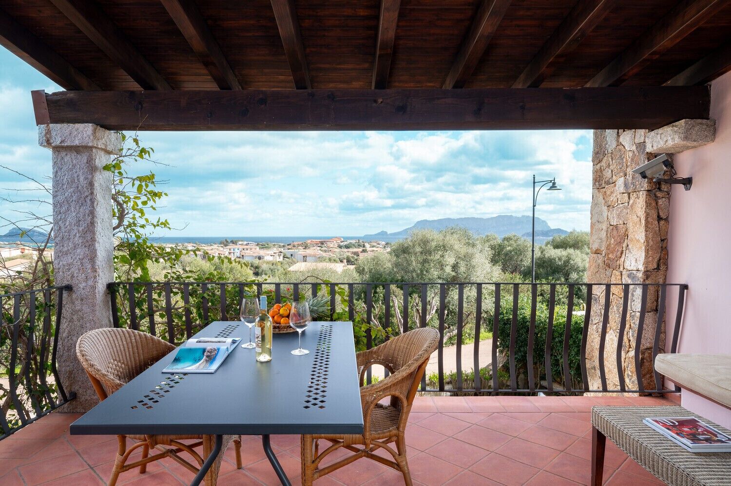 Un área de estar al aire libre techada con una mesa, sillas y vistas del paisaje.