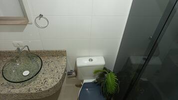 Ein Badezimmer mit einem Granitwaschbecken, Toilette und einer Duschkabine aus Glas.