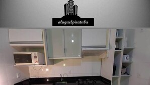 A kitchen with white cabinets, a microwave, a stove, and a built-in oven. - Apto 102 Ed Gabriel na divisa do Parque (Piratuba)