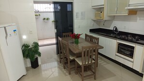 A kitchen with a dining table, chairs, a refrigerator, a microwave, an oven, and potted plants. - Apto 102 Ed Gabriel na divisa do Parque (Piratuba)