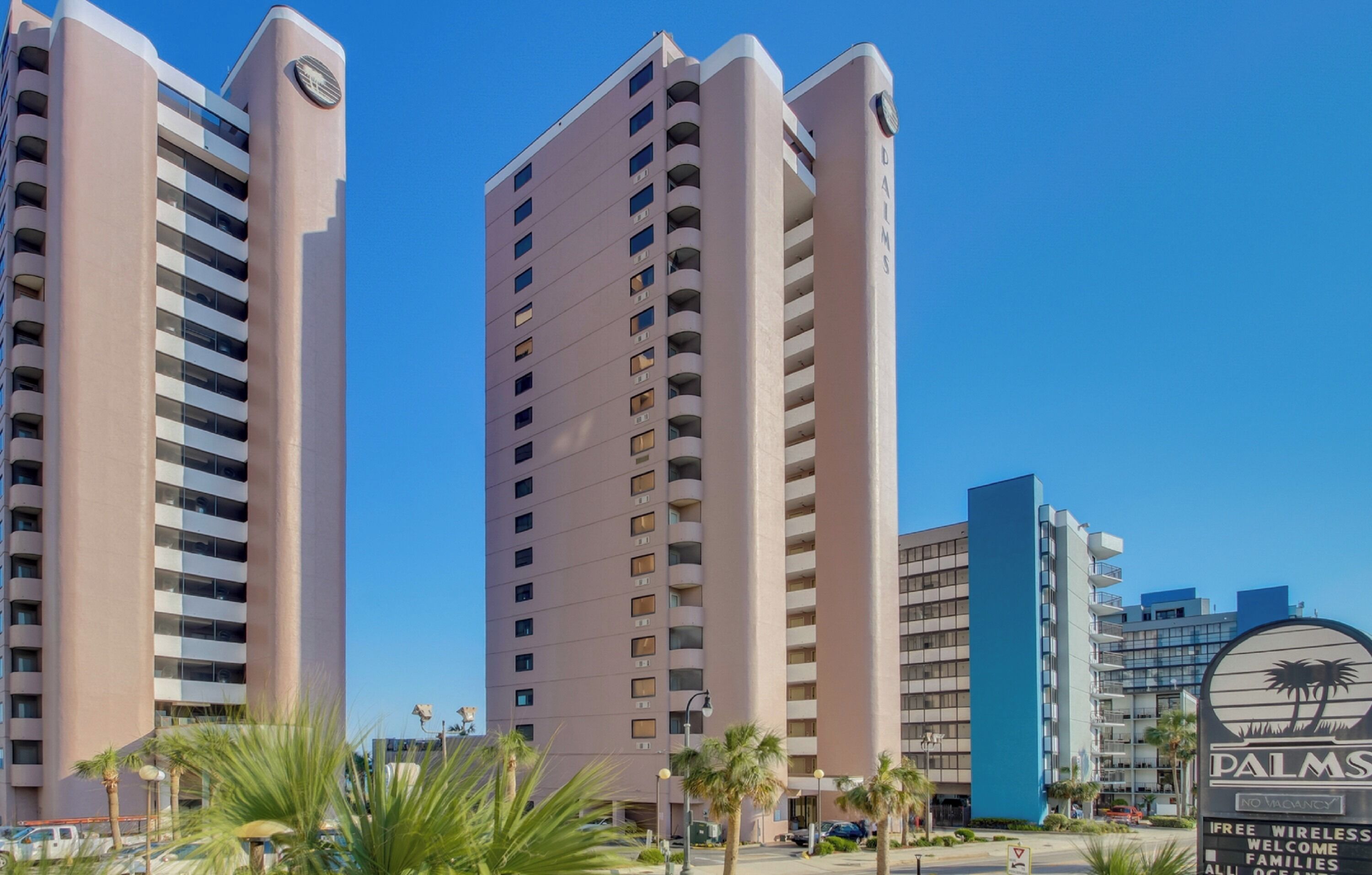 A high-rise hotel with multiple balconies and a clear blue sky.
