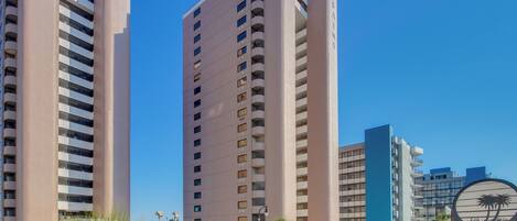 A high-rise hotel with multiple balconies and a clear blue sky.