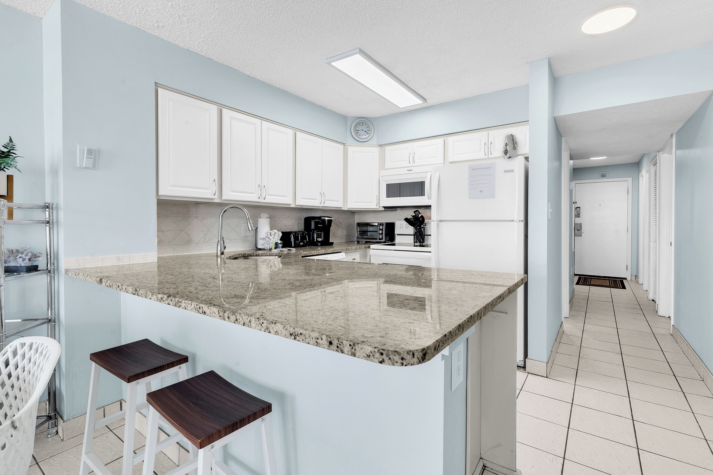 A modern kitchen with white cabinets, a granite countertop, and a stainless steel sink.